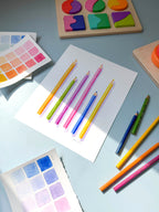 colored pencils watercolor archival print by Katie Sinclair on a desk with colored pencils and a wooden puzzle.