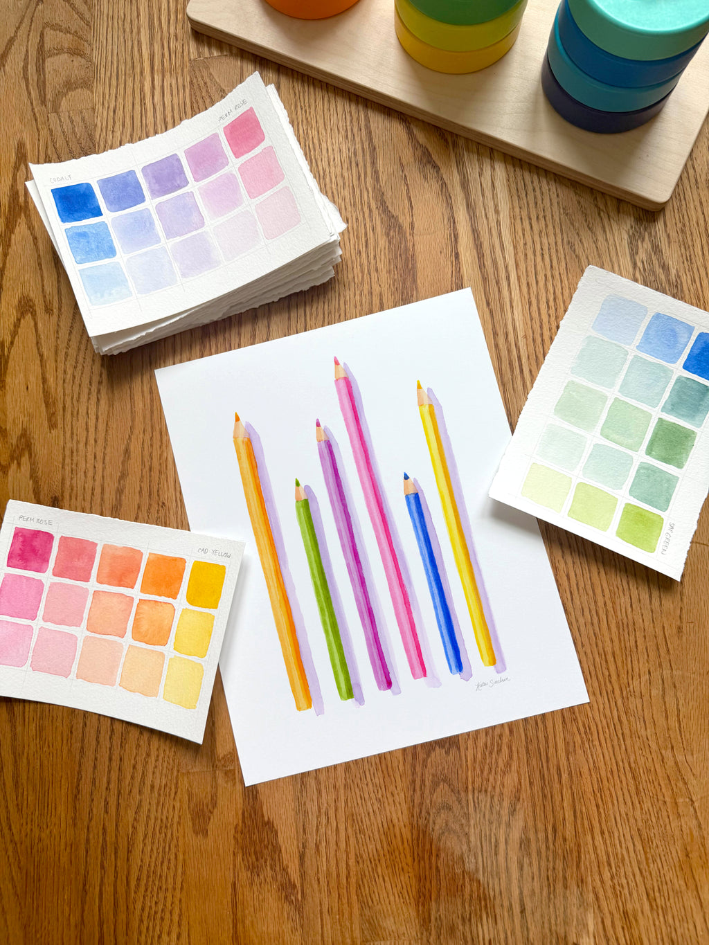 colorful watercolor of pencils archival print, surrounded by geometric toys on a wooden surface.  hand-painted by katie sinclair and perfect for a playroom or kid bedroom.