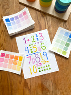 colorful watercolor numbers and shapes art print, surrounded by geometric toys on a wooden surface.  hand-painted by katie sinclair and perfect for a playroom or kid bedroom.