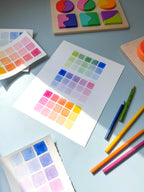 color swatch watercolor archival print by Katie Sinclair on a desk with colored pencils and a wooden puzzle.