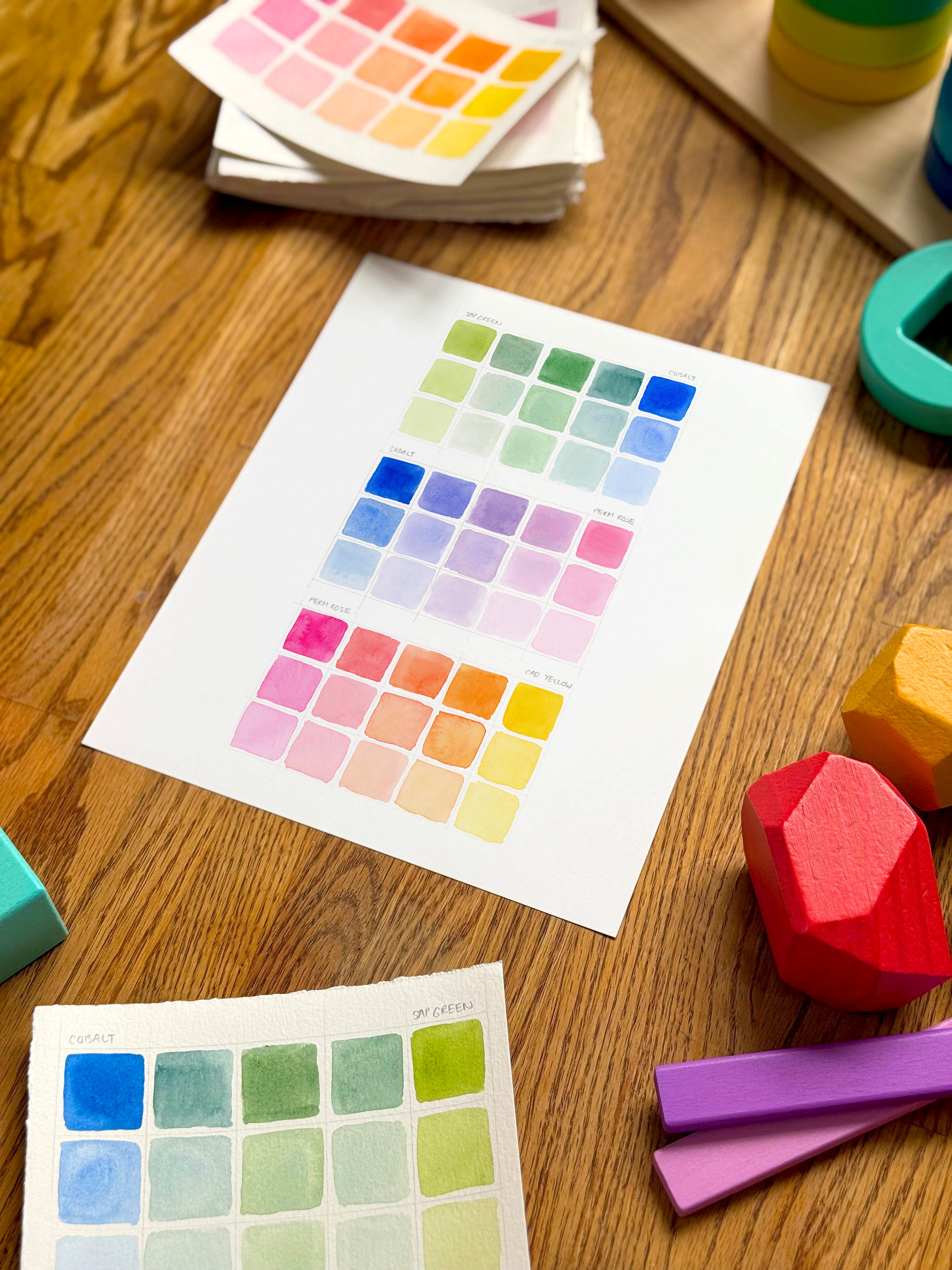 colorful watercolor swatch art print, surrounded by geometric toys on a wooden surface.  hand-painted by katie sinclair and perfect for a playroom or kid bedroom.