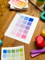 pink and blue color swatch watercolor art print, surrounded by geometric toys on a wooden surface