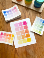 pink and yellow color swatch watercolor art print, surrounded by geometric toys on a wooden surface