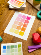 pink and yellow color swatch watercolor art print, surrounded by geometric toys on a wooden surface