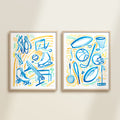 Two framed colorful playful sports watercolor art prints in frames featuring tennis, soccer, ballet and baseball for kids nursery or playroom wall décor.  The main colors are blue, yellow and orange, and green.