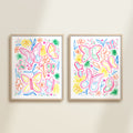 Two framed colorful pink, yellow, blue, green, and orange watercolor garden-themed artworks on a beige wall, featuring a butterflies and flowers.
