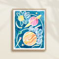 Framed colorful watercolor artwork of space-themed design with planets, stars, and a galaxy.