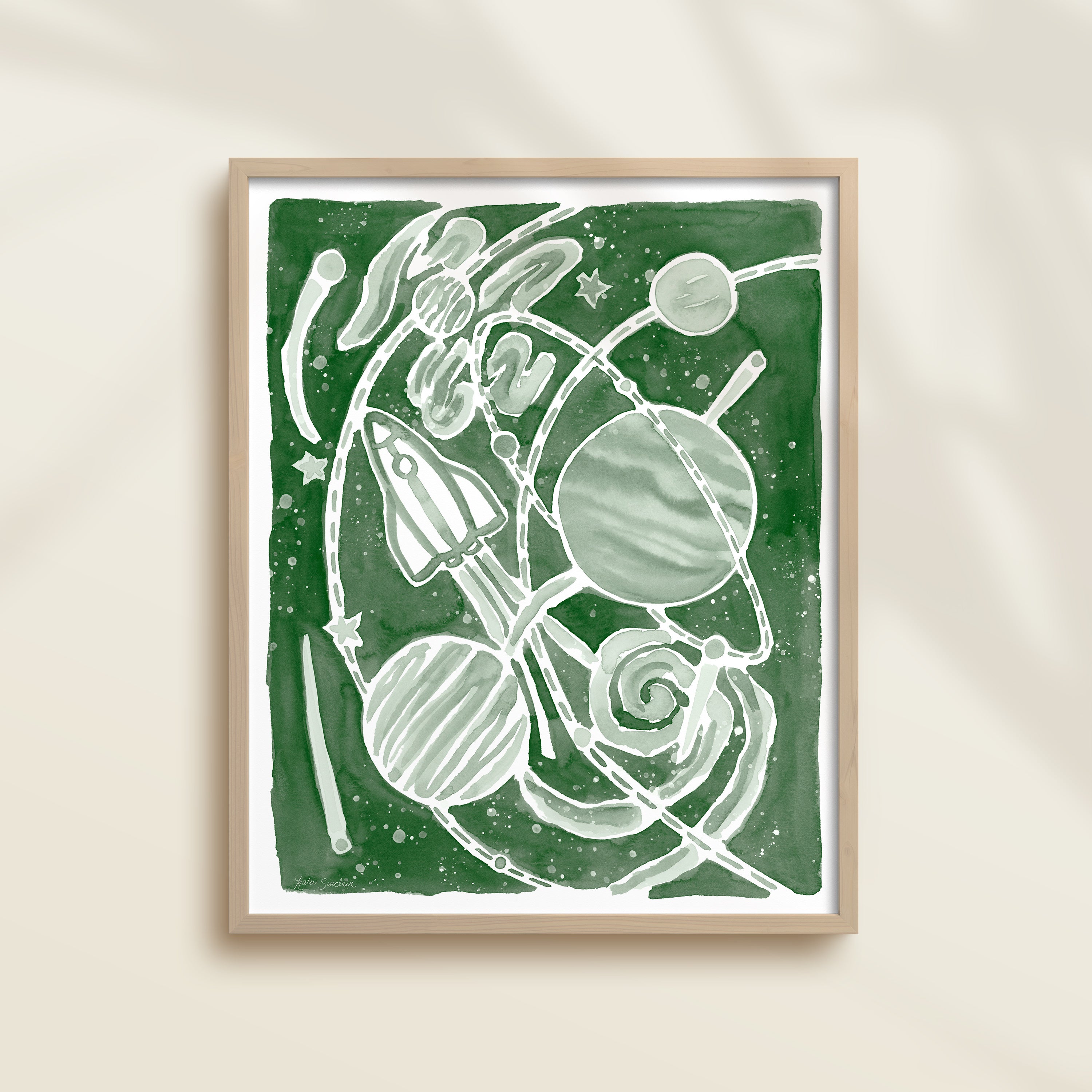 Framed green watercolor artwork of space-themed design with planets, stars, and a rocket ship.