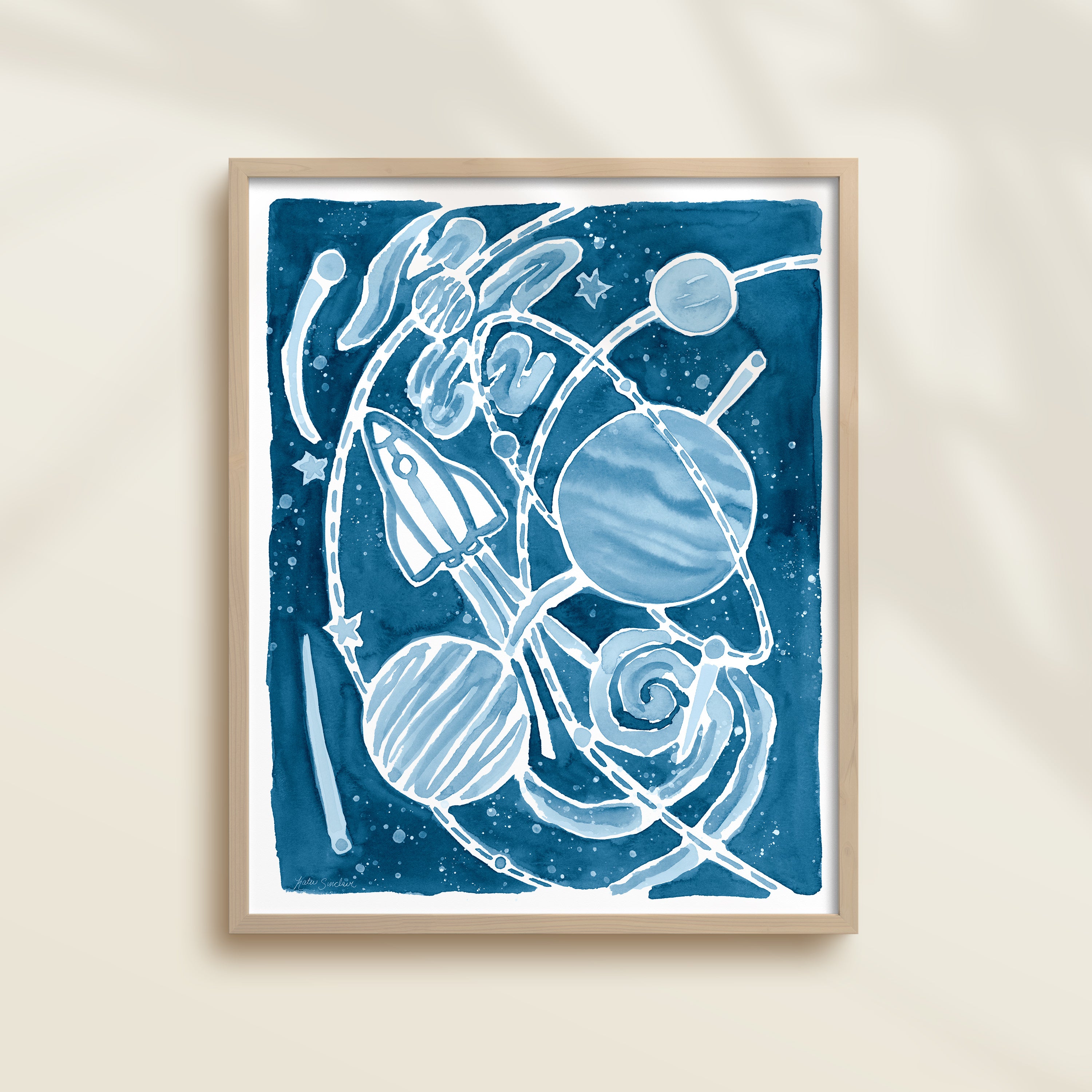 Framed blue watercolor artwork of space-themed design with planets, stars, and a rocket ship.