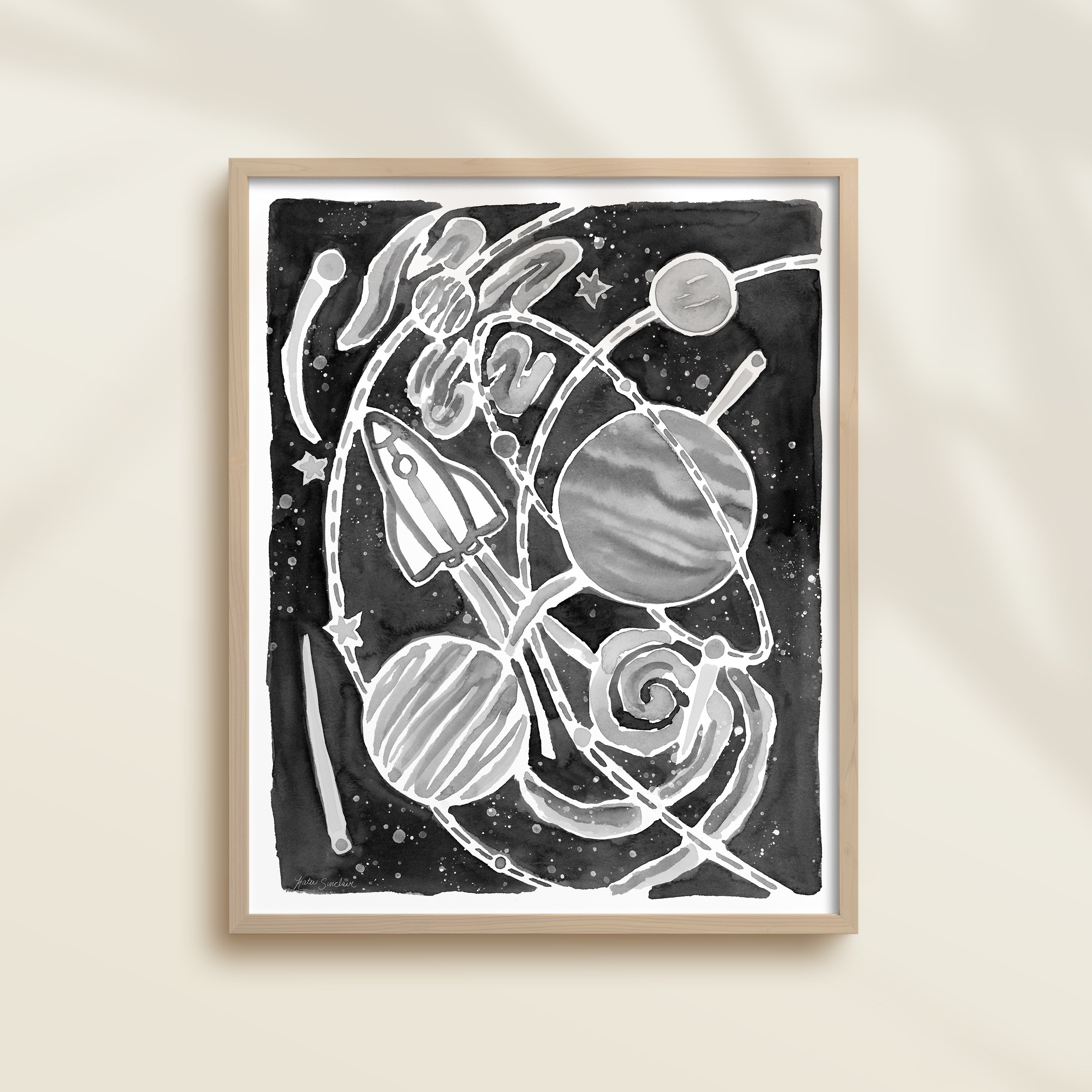 Framed black and white watercolor artwork of space-themed design with planets, stars, and a rocket ship.