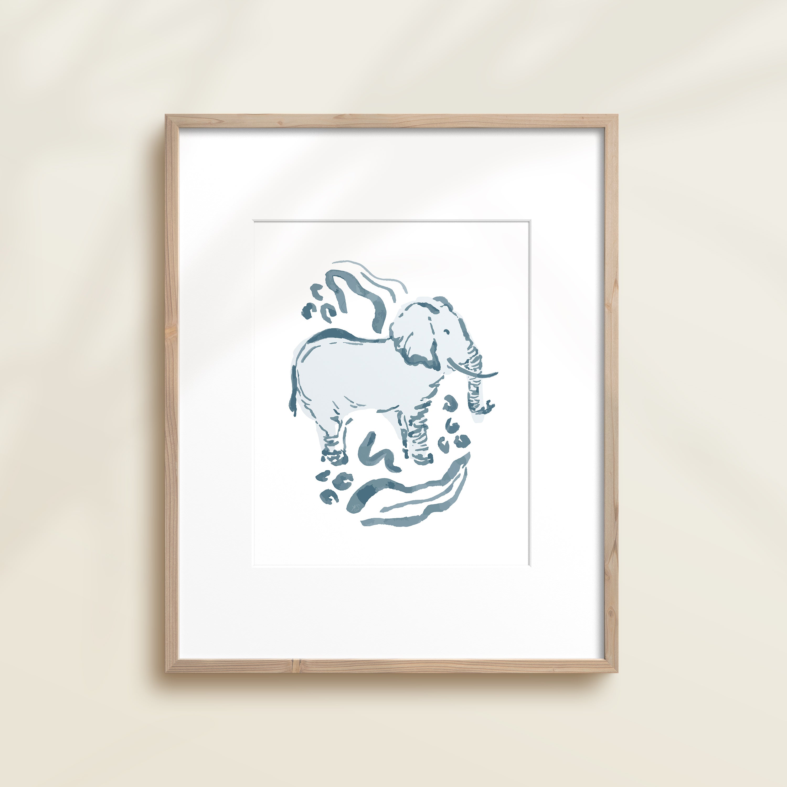 A framed watercolor print by Katie Sinclair of a elephant surrounded by  foliage, displayed on a wall.  This image showcases the blue color version.