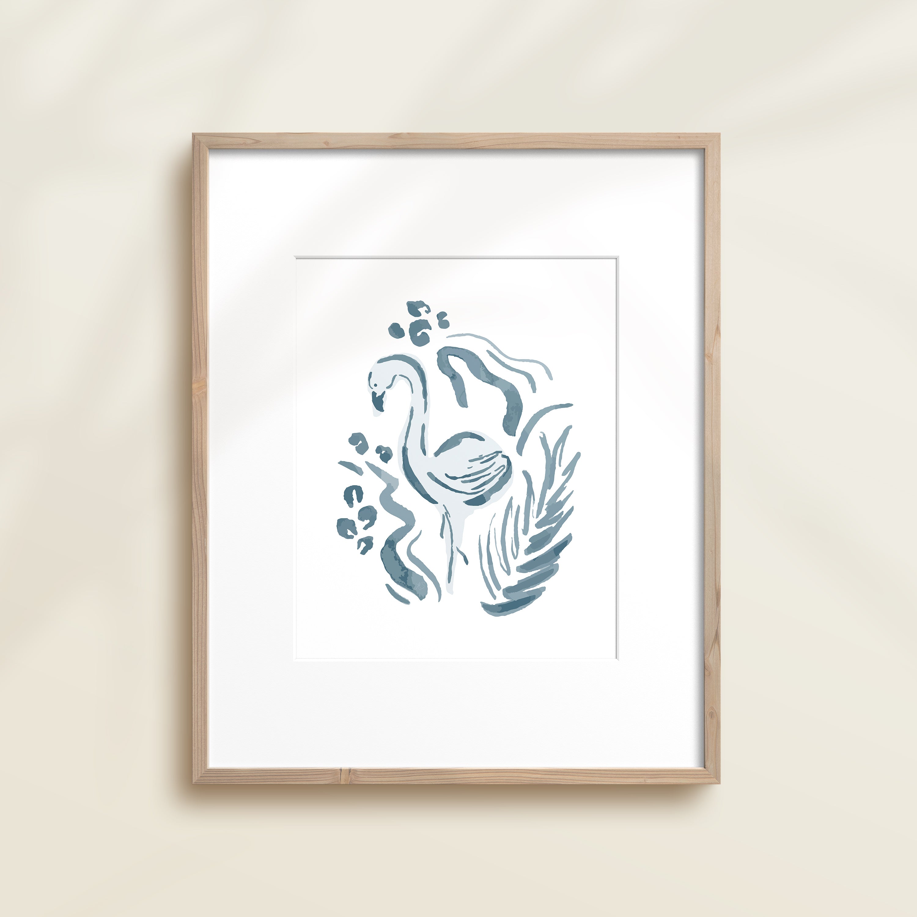 A framed watercolor print by Katie Sinclair of a flamingo surrounded by  foliage, displayed on a wall.  This image showcases the blue color version.