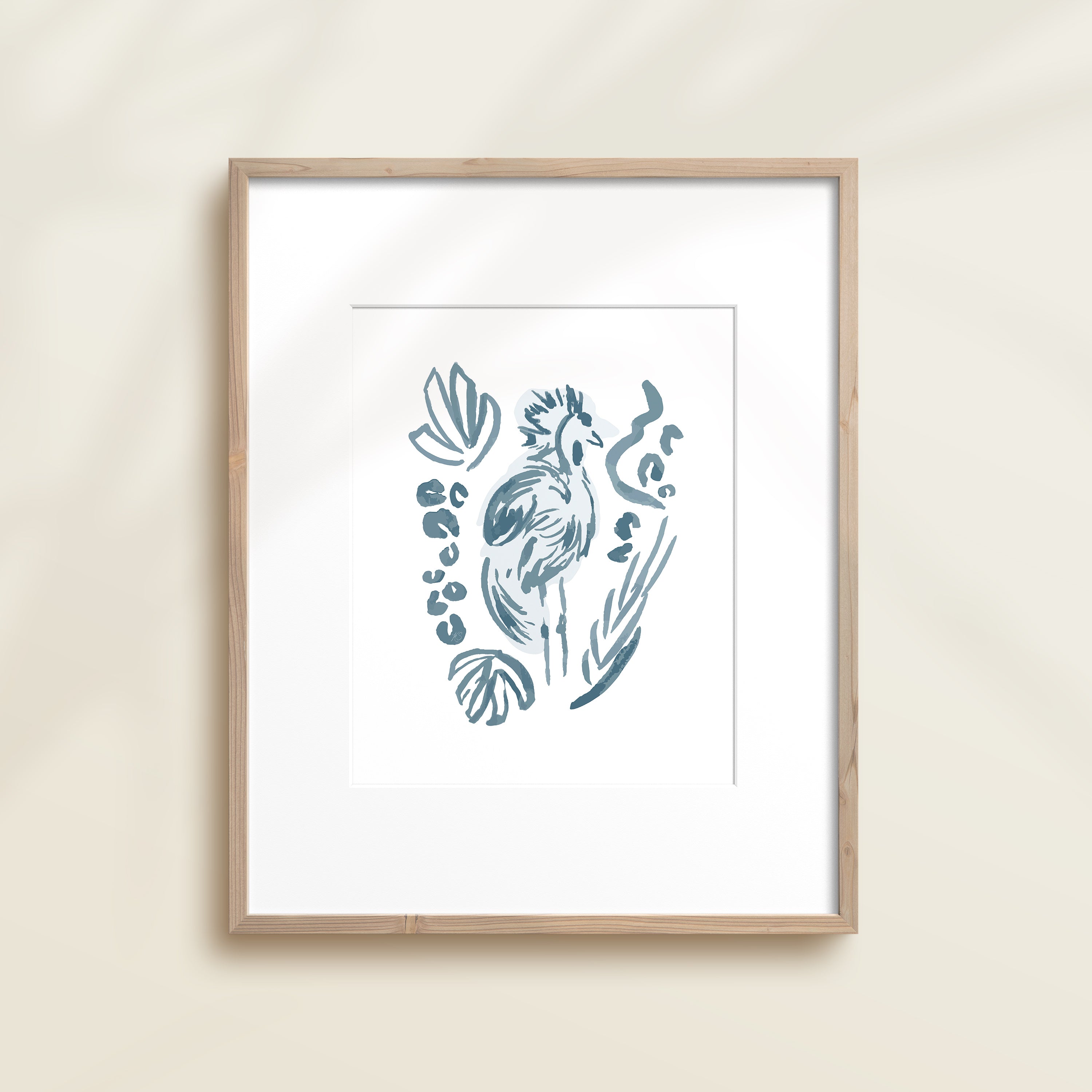 A framed watercolor print by Katie Sinclair of a tropical bird surrounded by  foliage, displayed on a wall.  This image showcases the blue color version.