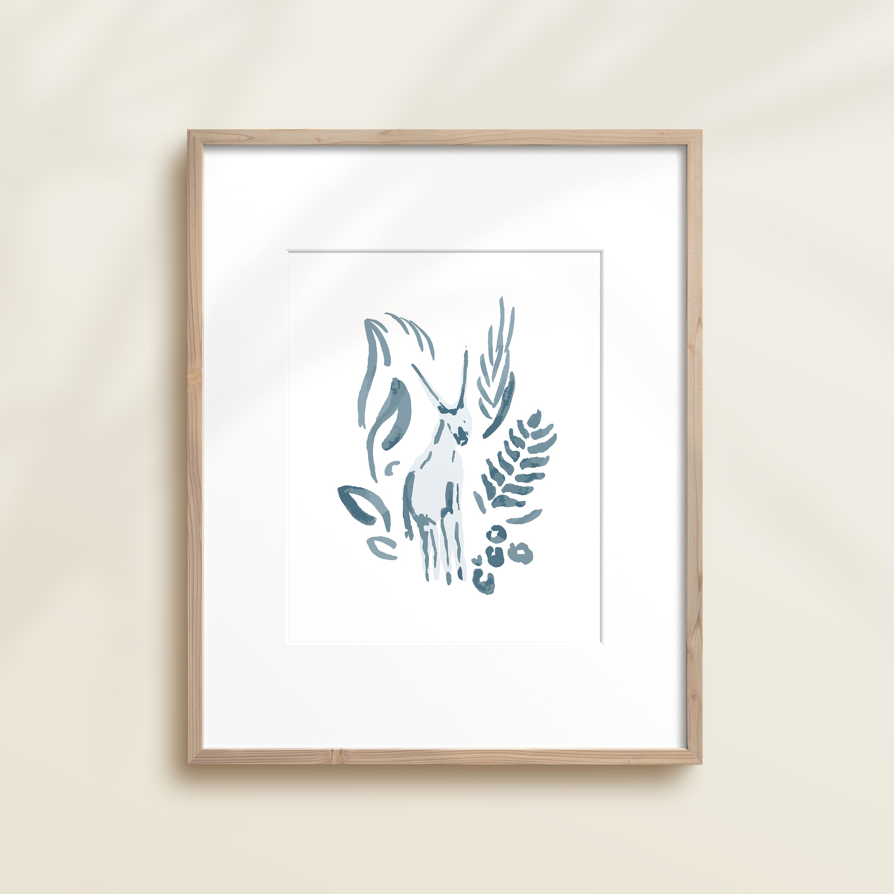 A framed watercolor print by Katie Sinclair of an antelope surrounded by  foliage, displayed on a wall.  This image showcases the blue color version.