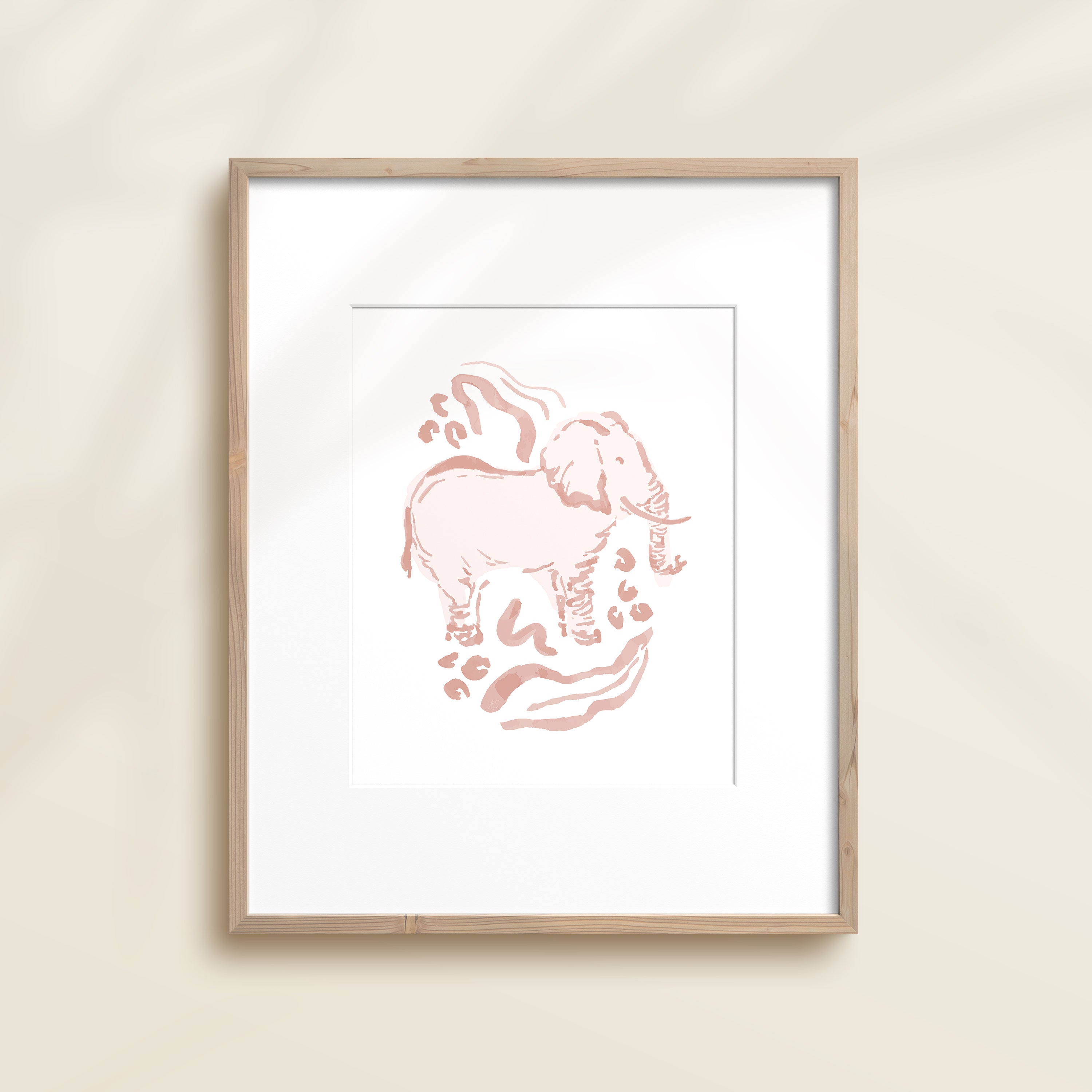 A framed watercolor print by Katie Sinclair of a elephant surrounded by  foliage, displayed on a wall.  This image showcases the pink color version.