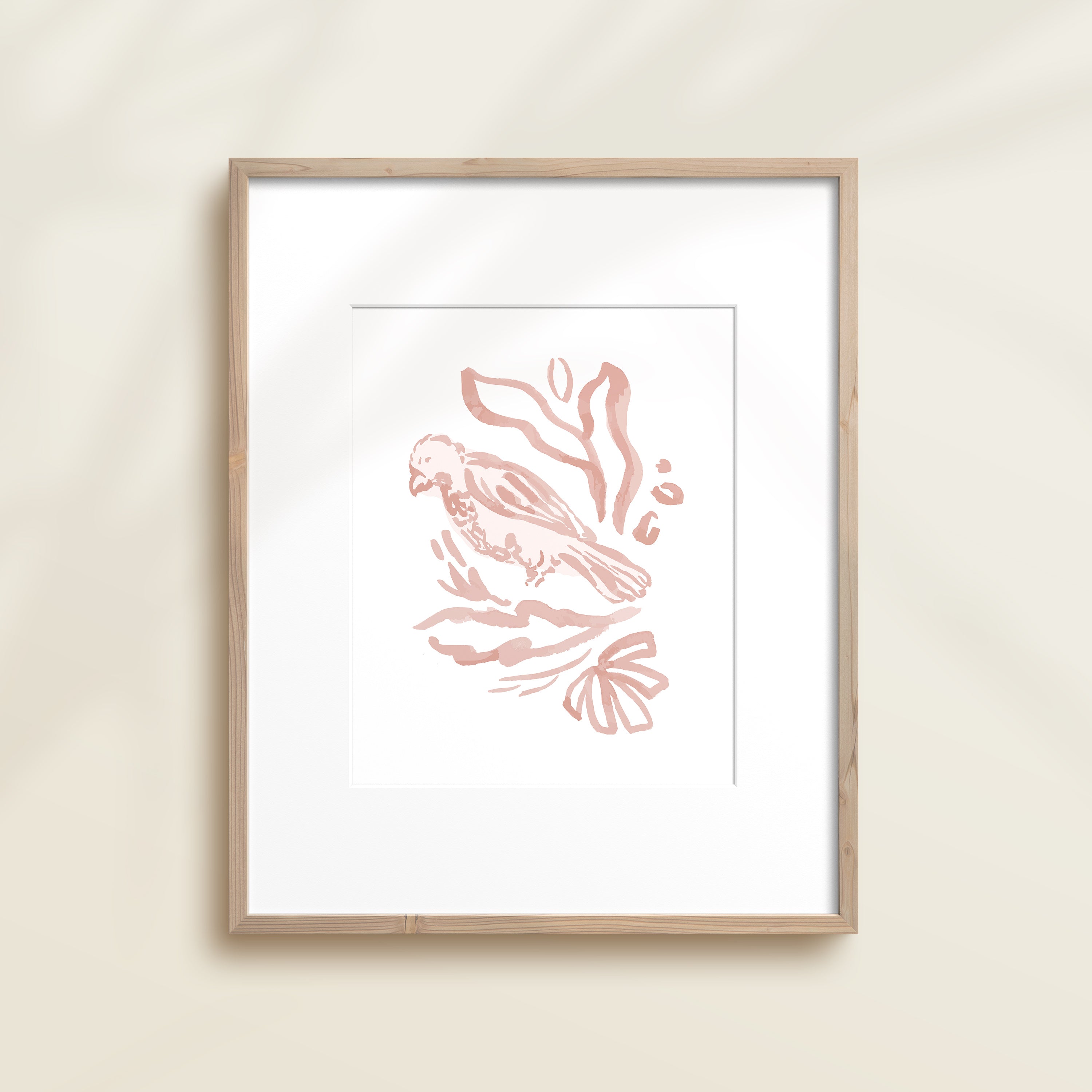 A framed watercolor print by Katie Sinclair of a bird surrounded by  foliage, displayed on a wall.  This image showcases the pink color version.