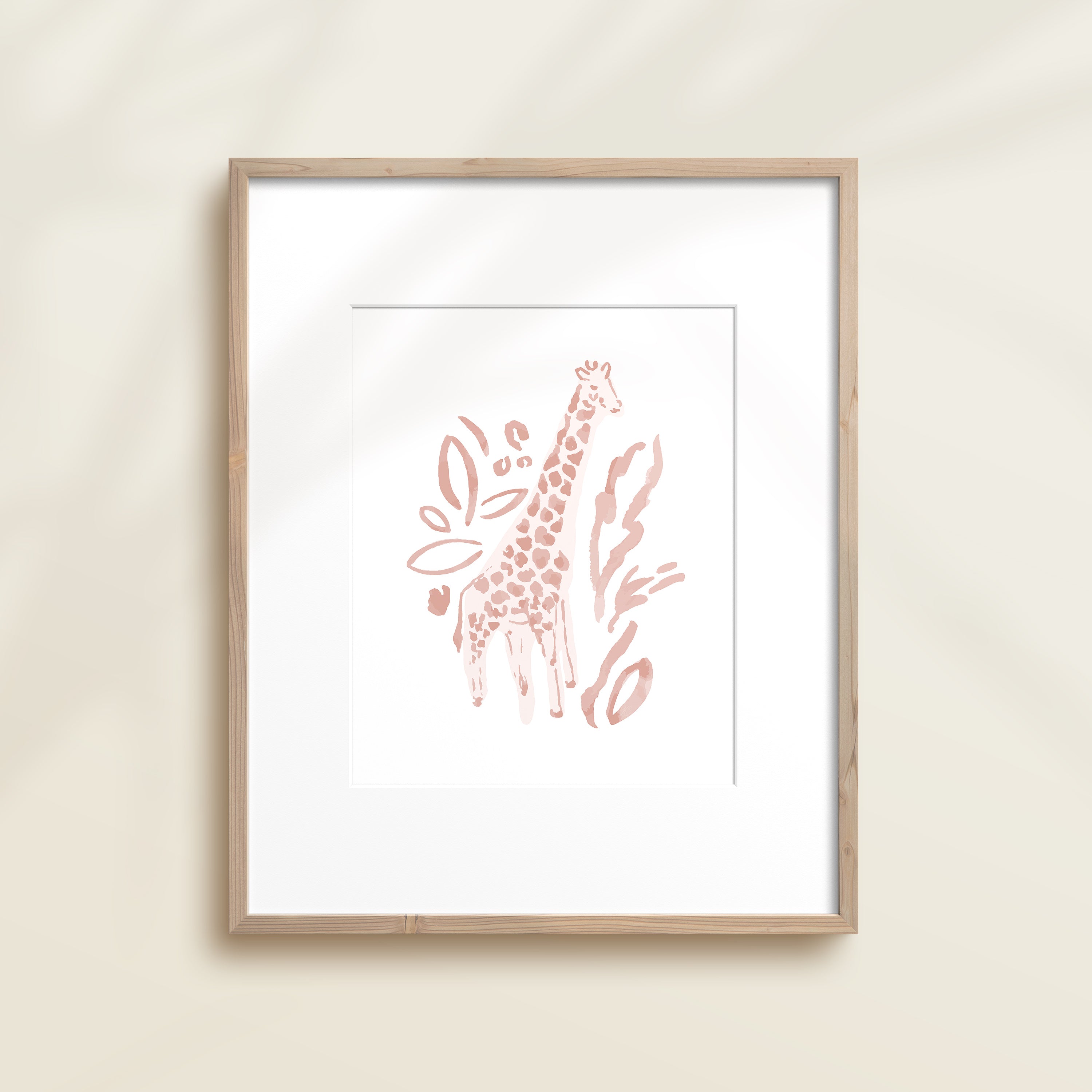 A framed watercolor print by Katie Sinclair of a giraffe surrounded by  foliage, displayed on a wall.  This image showcases the pink color version.
