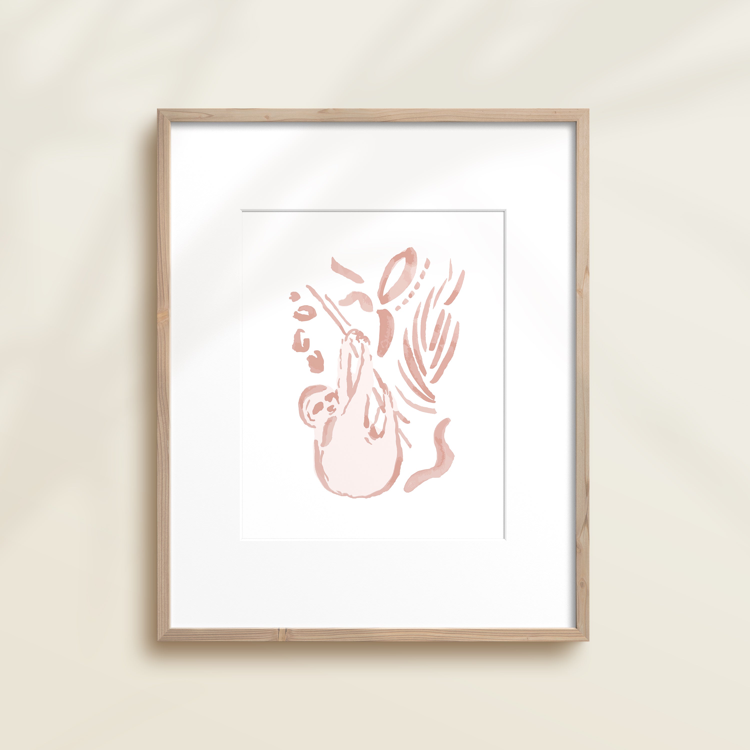 A framed watercolor print by Katie Sinclair of a sloth surrounded by  foliage, displayed on a wall.  This image showcases the pink color version.