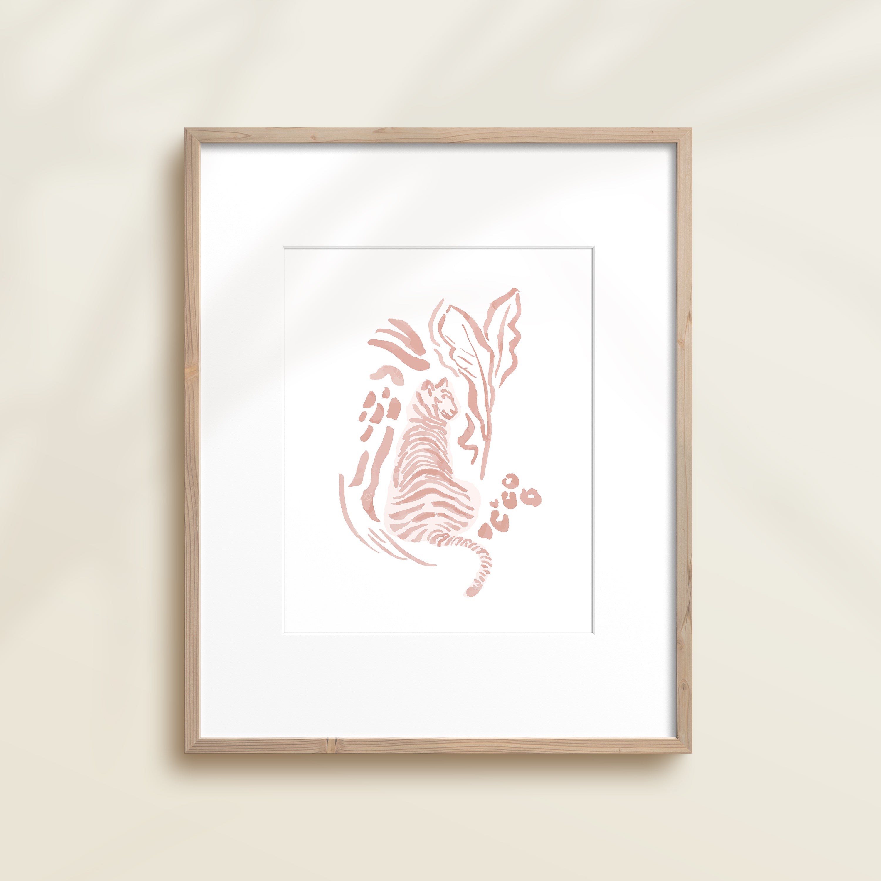 A framed watercolor print by Katie Sinclair of an tiger surrounded by  foliage, displayed on a wall.  This image showcases the pink color version.