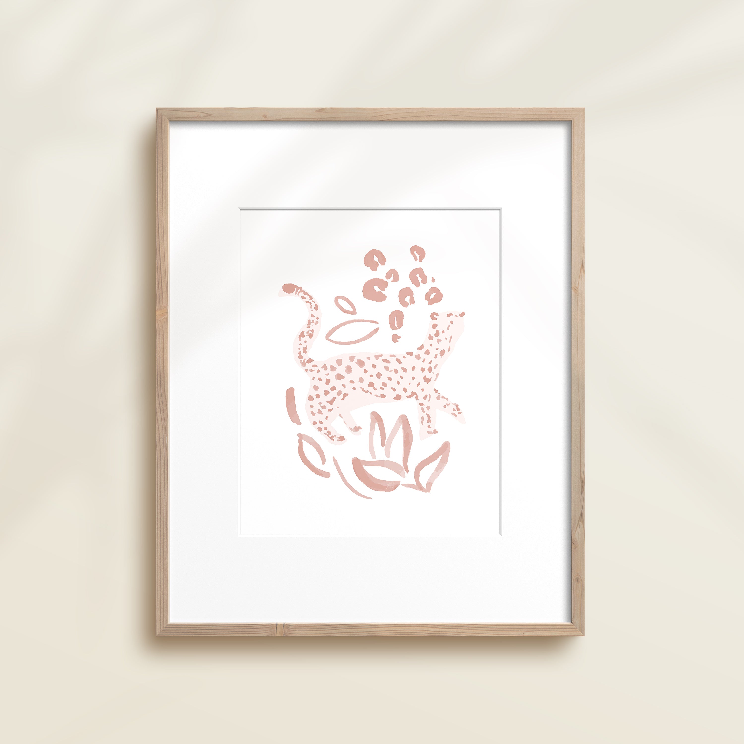 A framed watercolor print by Katie Sinclair of an cheetah surrounded by  foliage, displayed on a wall.  This image showcases the pink color version.