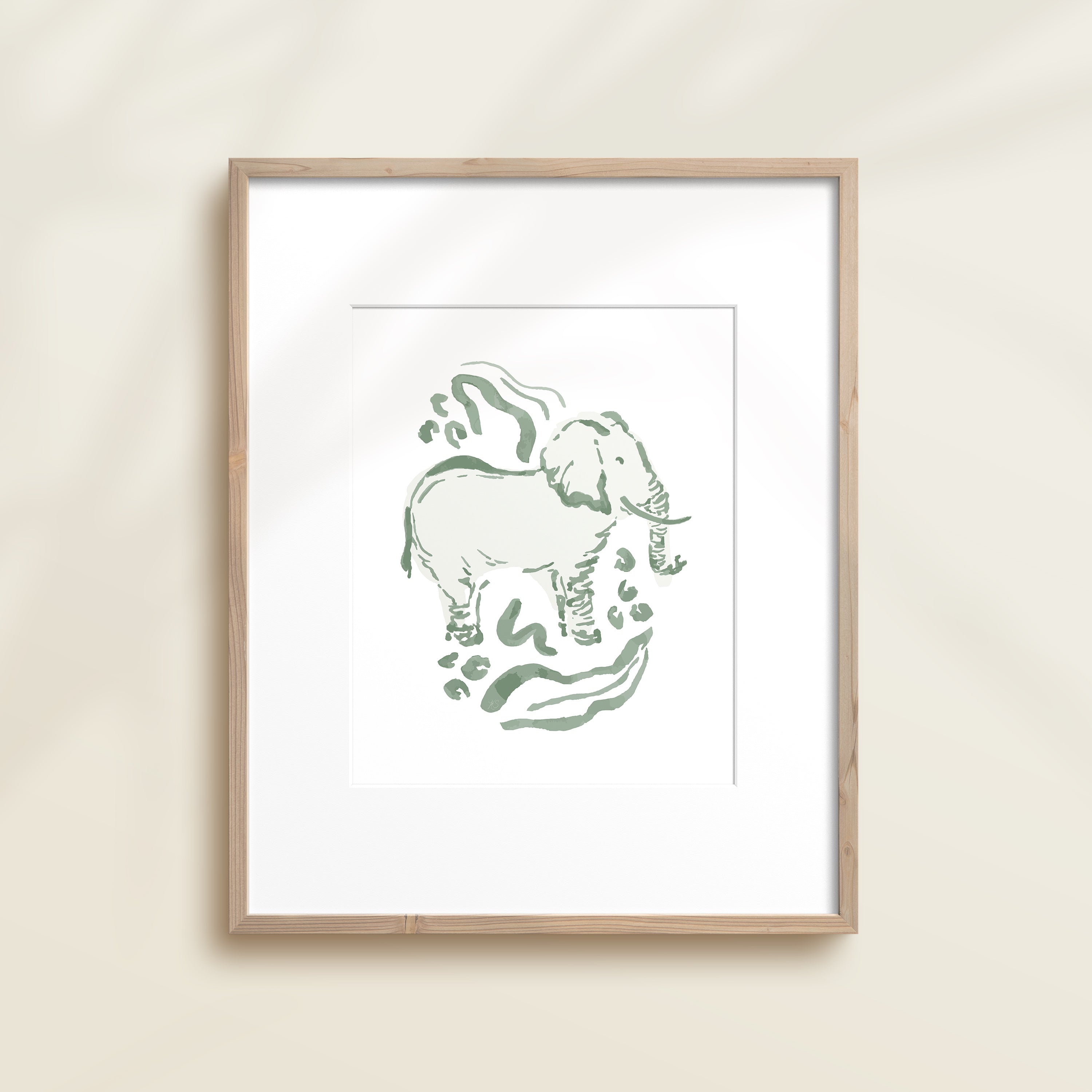 A framed watercolor print by Katie Sinclair of an elephant surrounded by  foliage, displayed on a wall.  This image showcases the green color version.