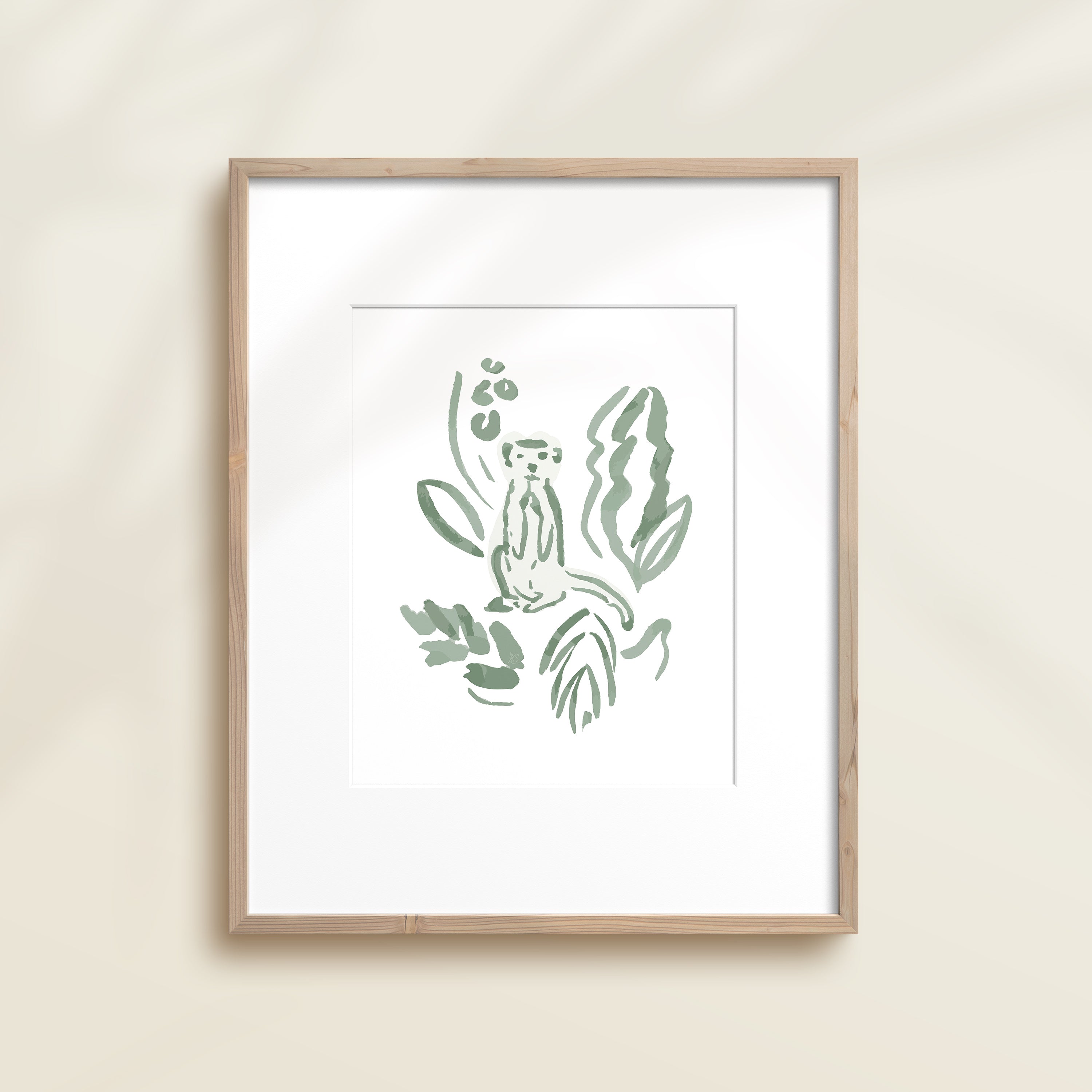 A framed watercolor print by Katie Sinclair of an meercat surrounded by  foliage, displayed on a wall.  This image showcases the green color version.