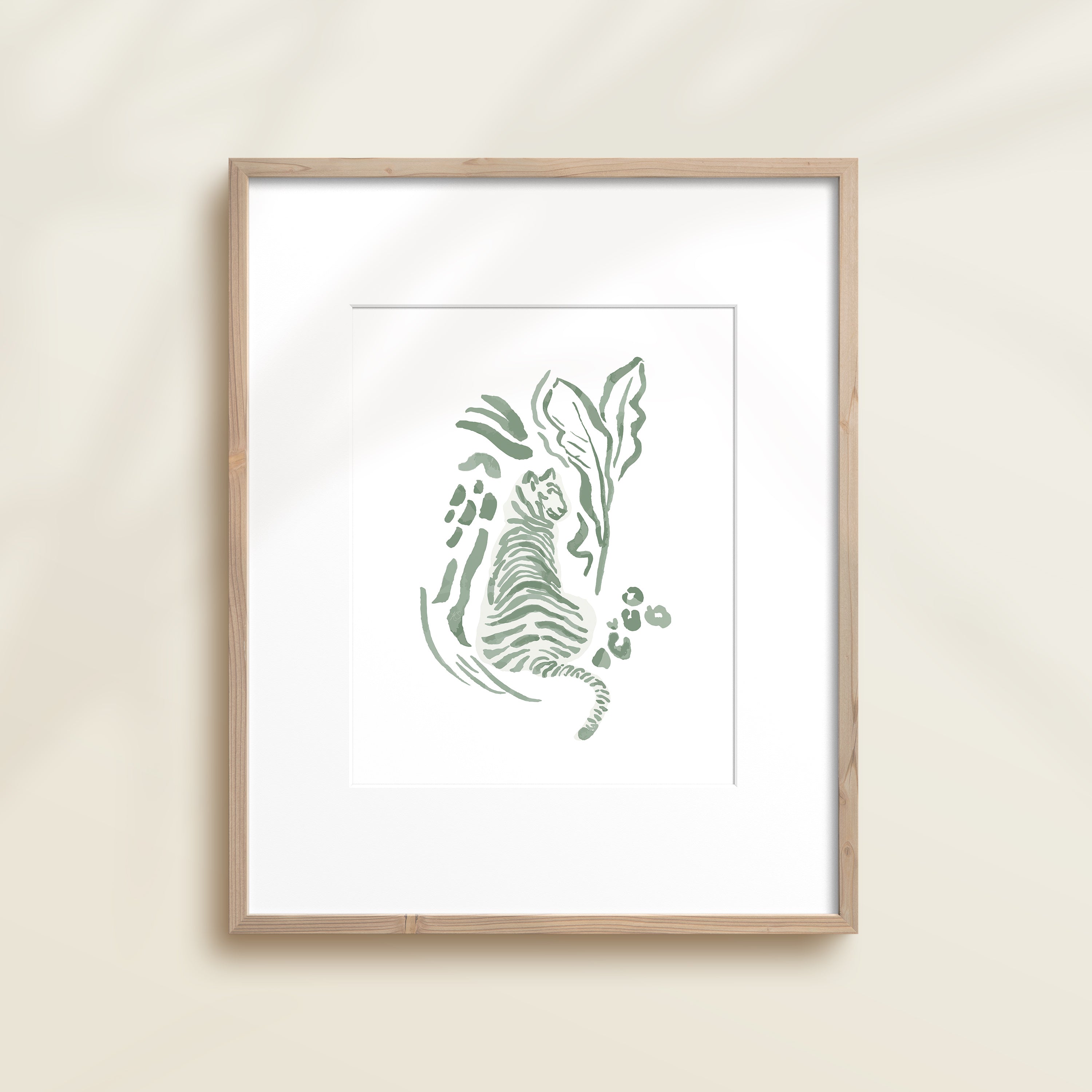 A framed watercolor print by Katie Sinclair of an tiger surrounded by  foliage, displayed on a wall.  This image showcases the green color version.