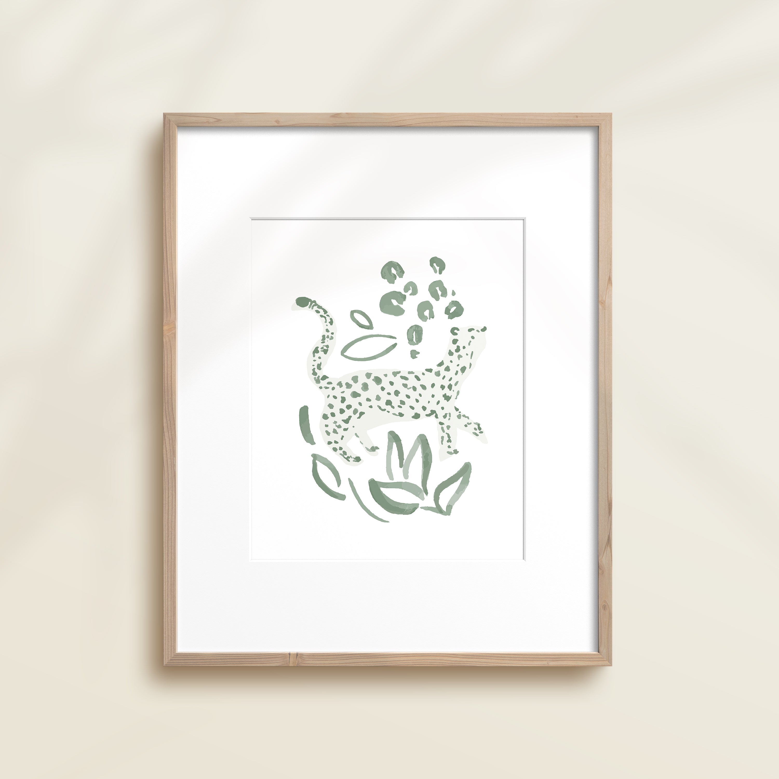 A framed watercolor print by Katie Sinclair of an cheetah surrounded by  foliage, displayed on a wall.  This image showcases the green color version.