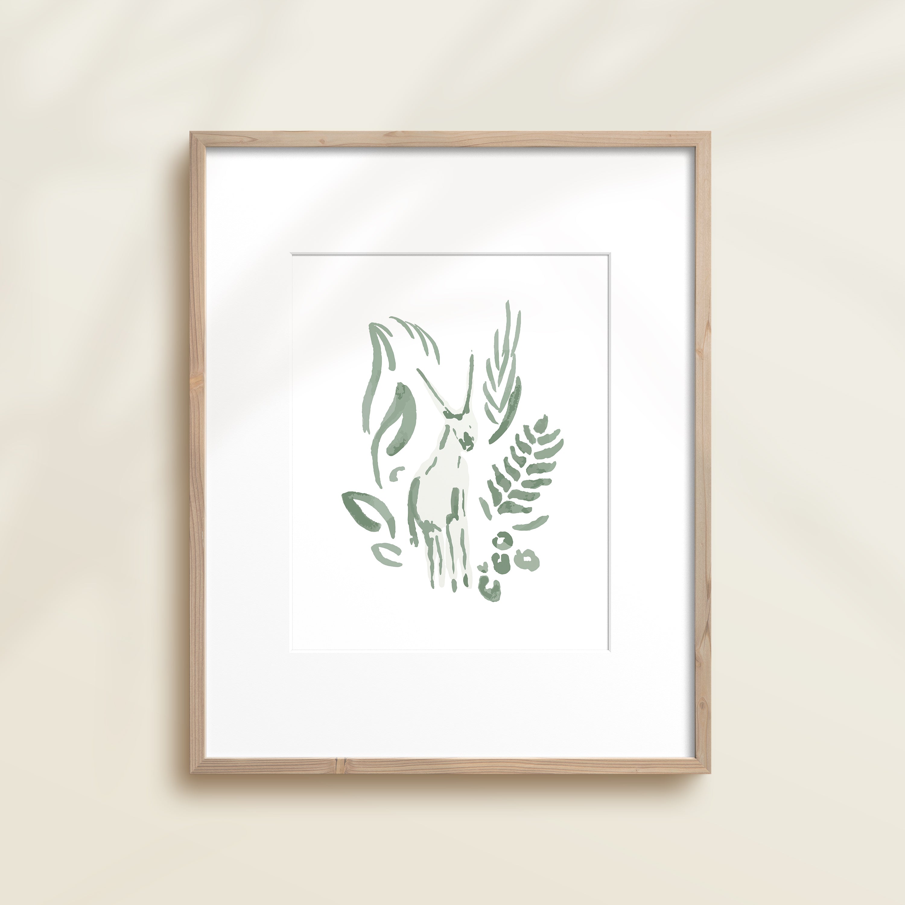 A framed watercolor print by Katie Sinclair of an antelope surrounded by  foliage, displayed on a wall.  This image showcases the green color version.