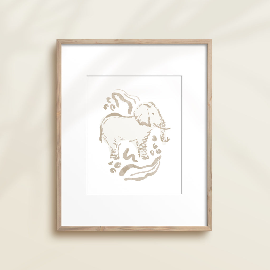 A framed watercolor print by Katie Sinclair of an elephant surrounded by  foliage, displayed on a wall.  This image showcases the gray color version.