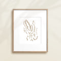 A framed watercolor print by Katie Sinclair of an lemur surrounded by  foliage, displayed on a wall.  This image showcases the gray color version.