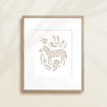 A framed watercolor print by Katie Sinclair of an zebra surrounded by  foliage, displayed on a wall.  This image showcases the gray color version.