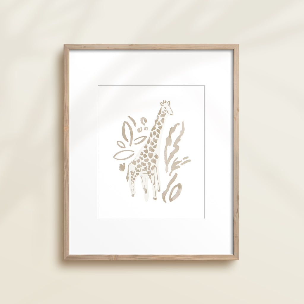 A framed watercolor print by Katie Sinclair of an giraffe surrounded by  foliage, displayed on a wall.  This image showcases the gray color version.
