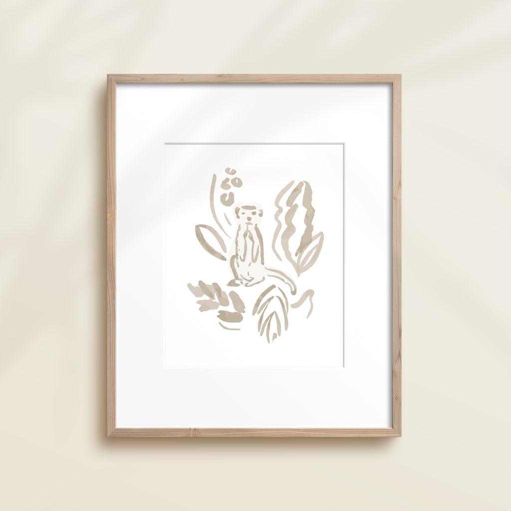 A framed watercolor print by Katie Sinclair of an meercat surrounded by  foliage, displayed on a wall.  This image showcases the gray color version.