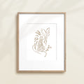A framed watercolor print by Katie Sinclair of an tiger surrounded by  foliage, displayed on a wall.  This image showcases the gray color version.