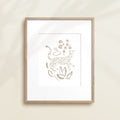 A framed watercolor print by Katie Sinclair of an cheetah surrounded by  foliage, displayed on a wall.  This image showcases the gray color version.
