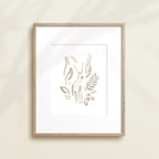 A framed watercolor print by Katie Sinclair of an antelope surrounded by  foliage, displayed on a wall.  This image showcases the gray color version.